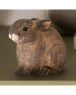 Bruin houten babykonijntje op een groene ondergrond, met een compact lichaam, breed liggend oor en zorgvuldig uitgesneden details rond de snuit en poten.
