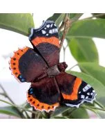 Houten Atalanta vlinder van Wildlife Garden tussen takken en bladeren, met een donkere vleugeltekening, feloranje dwarsbanden en gekartelde vleugelranden.