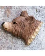Beschilderde houten berenkop als magneet op een grijs gespikkelde metalen ondergrond, met donkere neus, ronde oorschelpen en gesneden vachtlijnen.