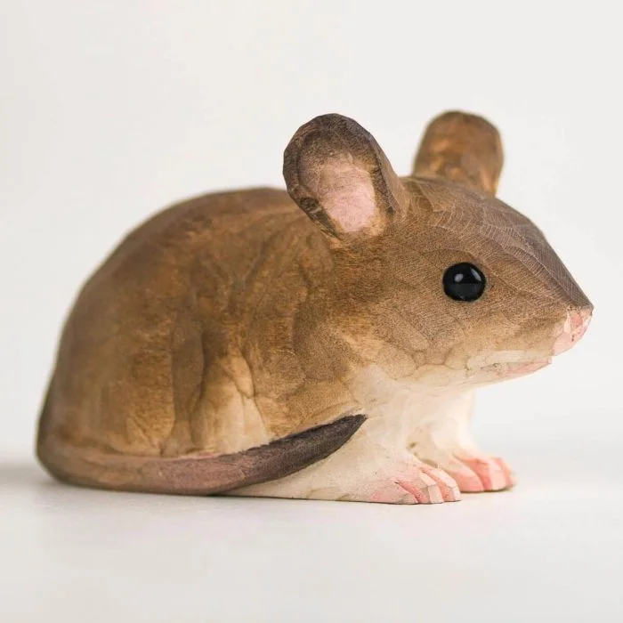 Bruine houten muis met een afgerond lichaam en lange dunne staart, gefotografeerd van dichtbij met opvallende zwarte kraalogen en roze binnenoren.