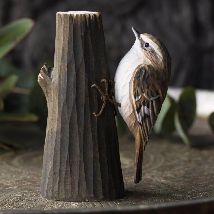 De DecoBird Boomkruiper is afgebeeld in zijn typische pose, kruipend tegen een boomstam.