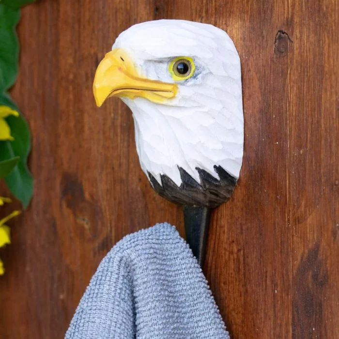 Decoratieve wandhaak met Amerikaanse zeearend van hout en metaal tegen een rustieke houten achtergrond